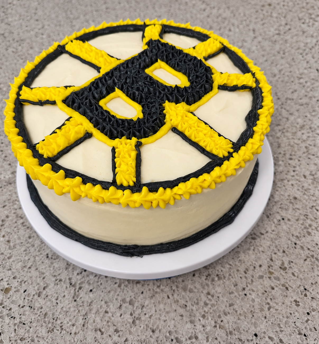 Round cake with a piped black and yellow Boston Bruins design