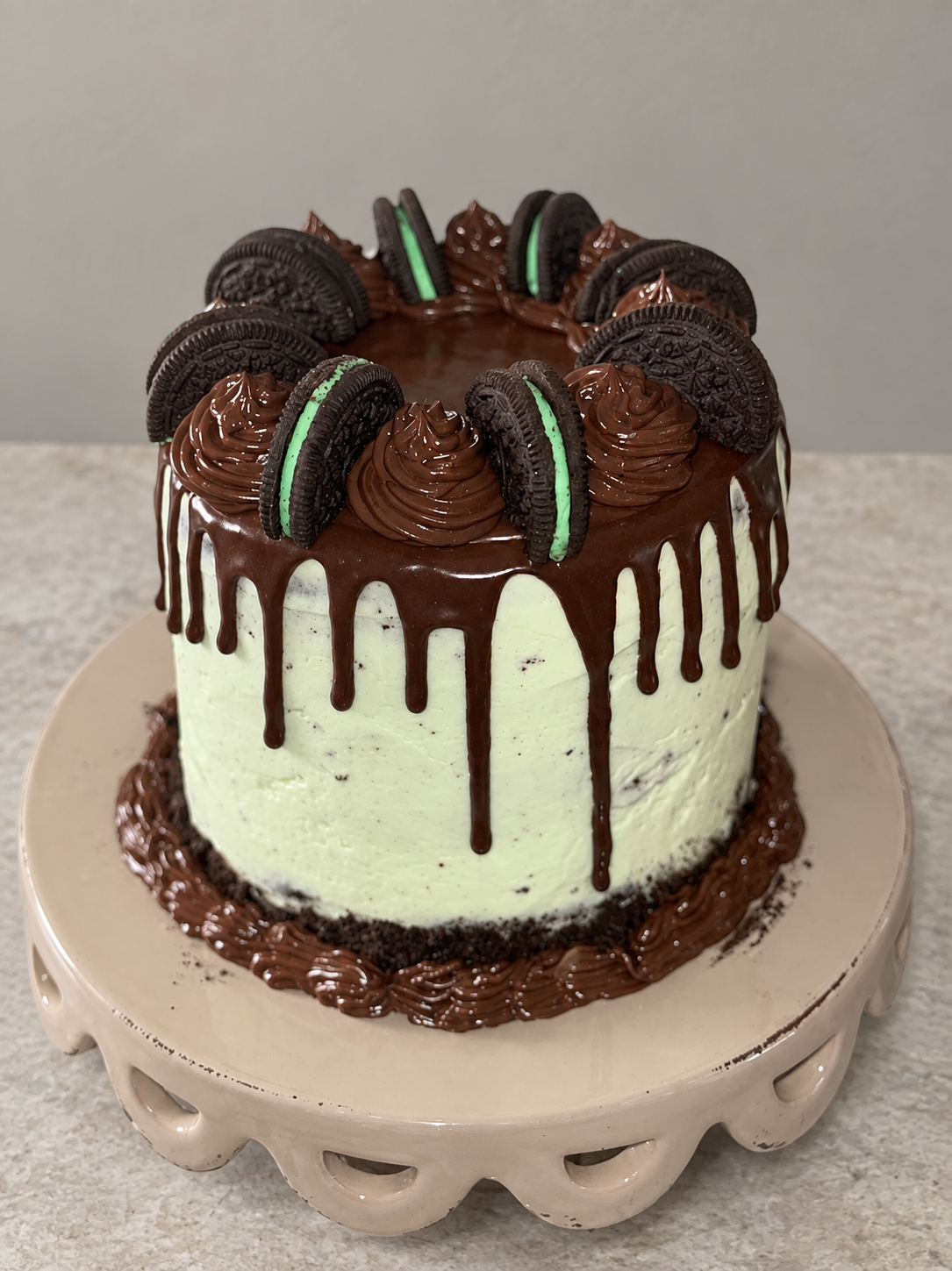 Mint-green cake topped with chocolate ganache drips and Oreo cookies